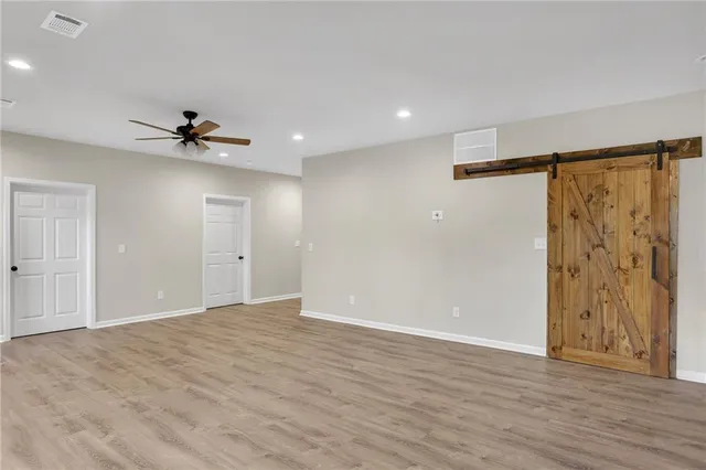 a view of an empty room with a ceiling fan window and wooden floor