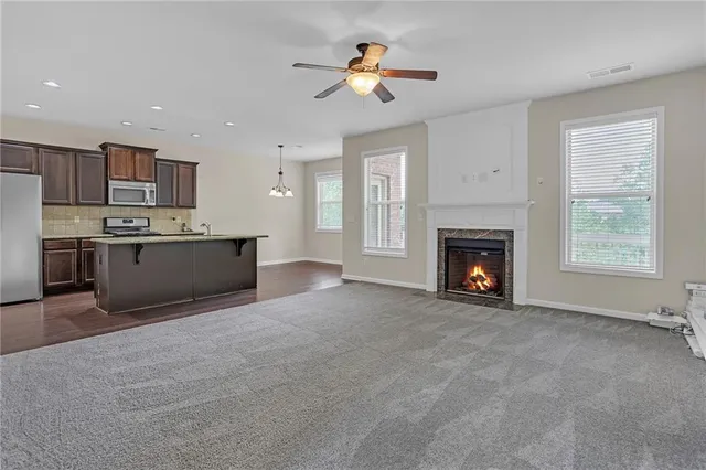 a view of kitchen with a fireplace a ceiling fan and a kitchen view