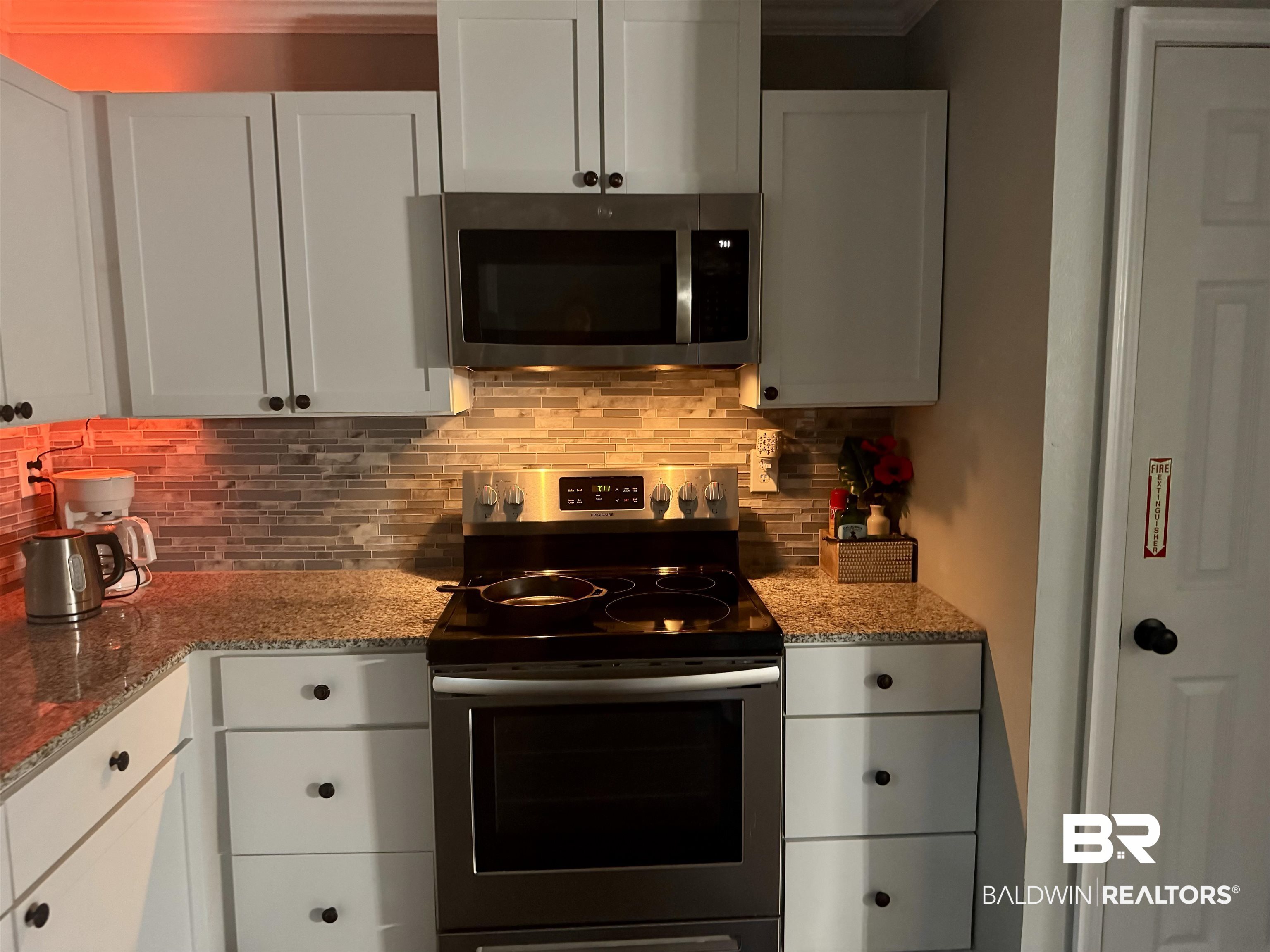 1302 Oak Street Daphne, AL 36526 - Photo 9 of 34 Kitchen with stainless steel appliances, light stone countertops, white cabinets, and tasteful backsplash