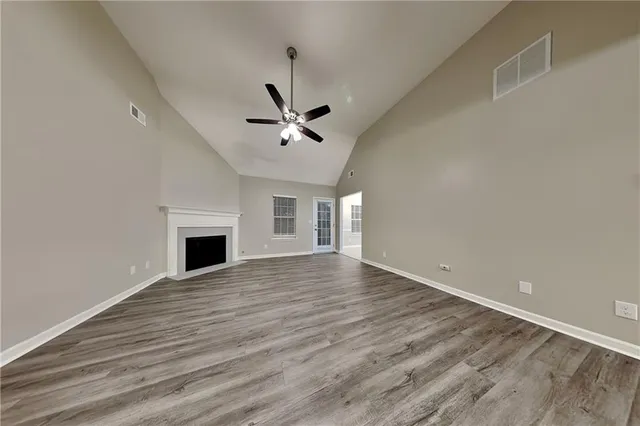 an empty room with wooden floor and ceiling fan