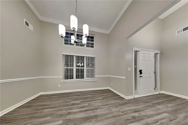 a view of a livingroom with wooden floor staircase and a kitchen space