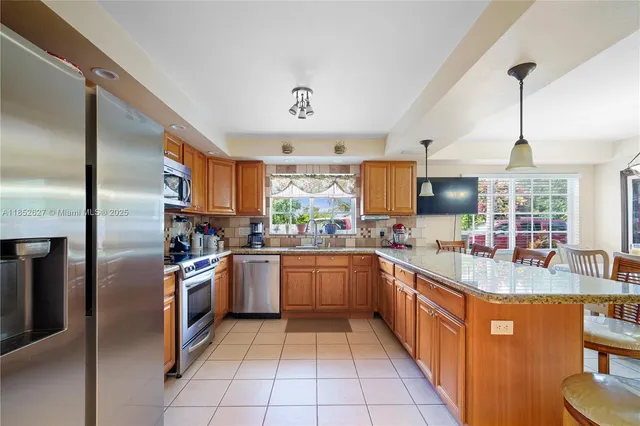a kitchen with stainless steel appliances granite countertop a sink and a refrigerator