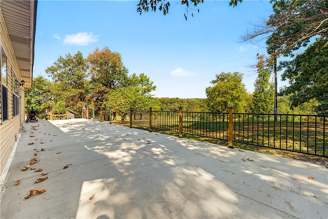 15282 Burgin Valley Road Gravette, AR 72736 - Photo 4 of 53 Expansive concrete patio with a black metal fence featuring wood posts