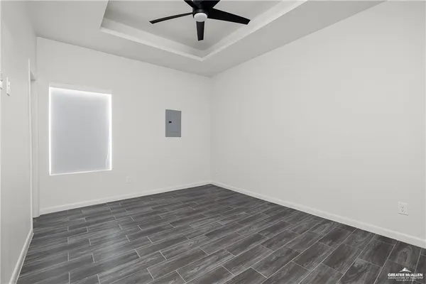 an empty room with a ceiling fan and wooden floor