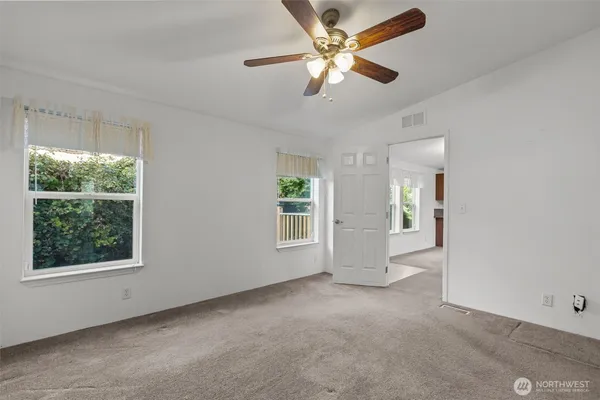 an empty room with windows and ceiling fan