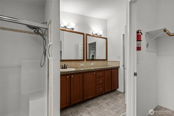 a bathroom with a granite countertop double vanity sink and mirror