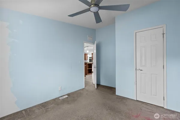 an empty room with a ceiling fan and carpet