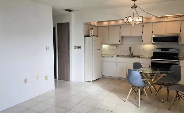 a kitchen with stainless steel appliances a table and chairs in it