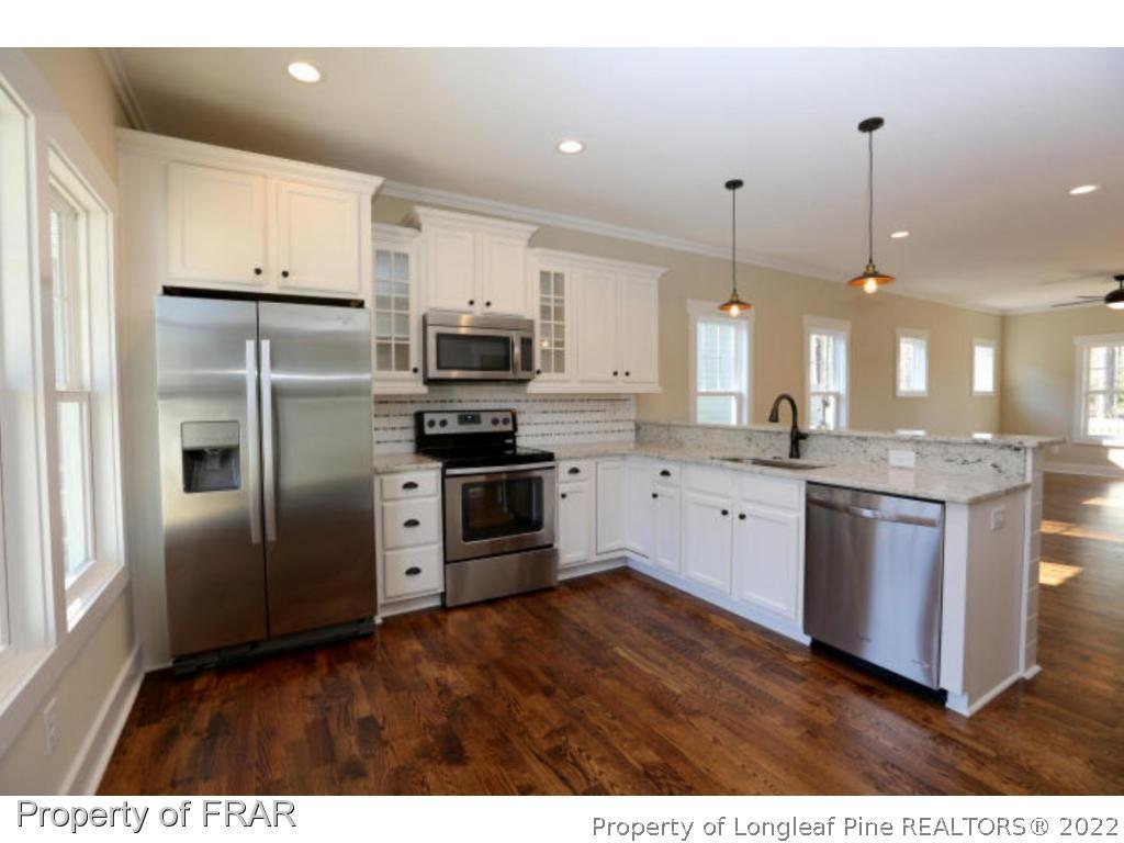 229 Springwood Way Southern Pines, NC 28387 - Photo 4 of 4 a kitchen with stainless steel appliances kitchen island granite countertop a refrigerator a sink dishwasher a stove and a refrigerator