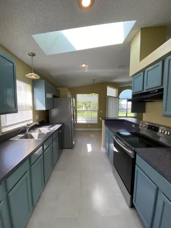a kitchen with stainless steel appliances granite countertop a sink a stove and a wooden floors