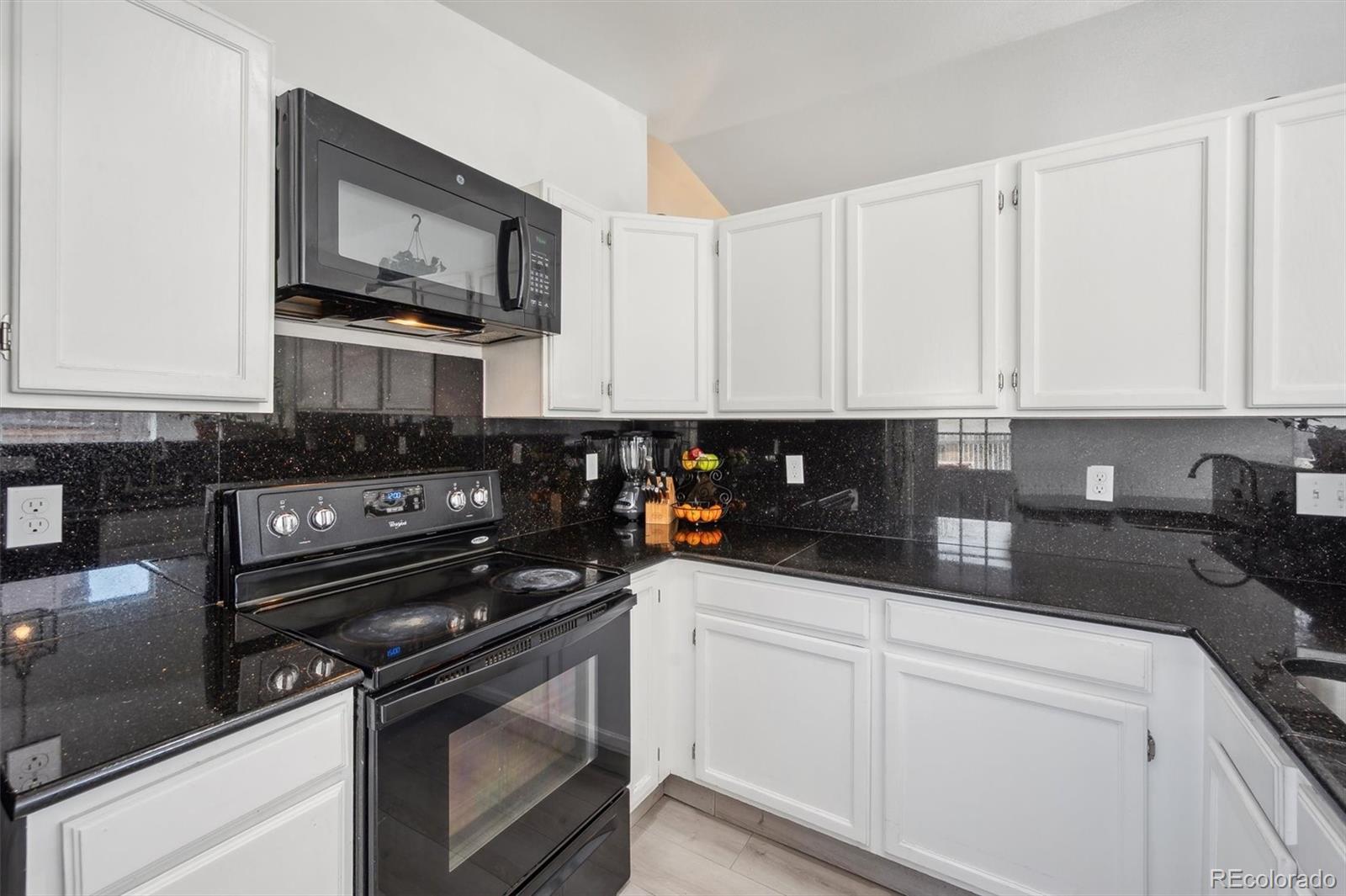 a kitchen with stainless steel appliances granite countertop white cabinets granite counter tops and a black granite counter tops