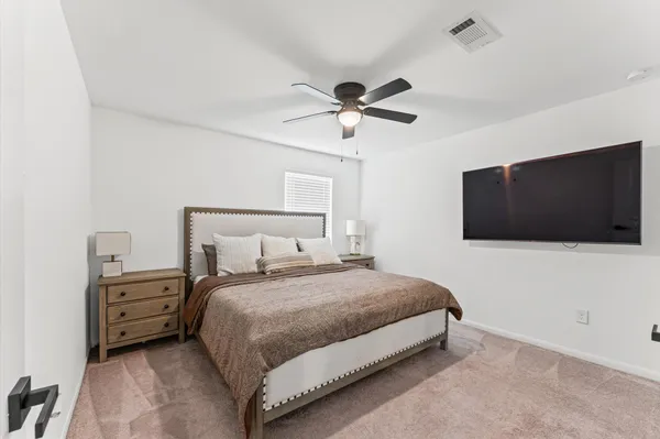 a bedroom with a bed a tv and wooden floor