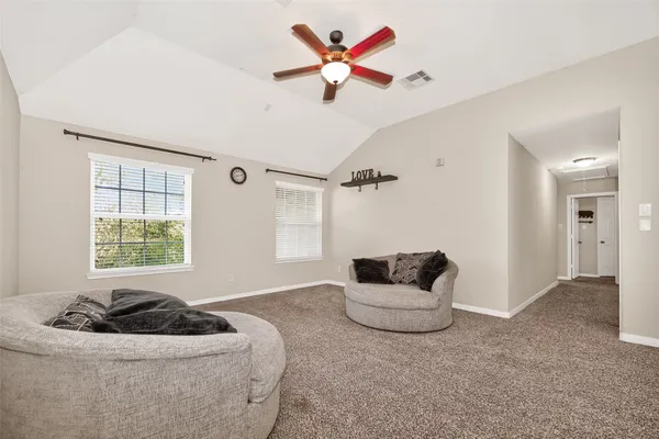 an empty room with chandelier fan and windows