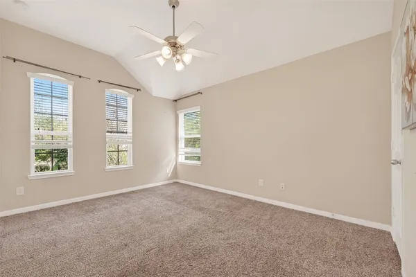 an empty room with chandelier fan and windows