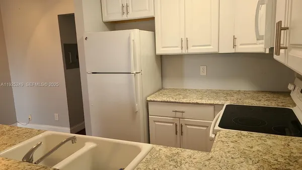 a kitchen with stainless steel appliances granite countertop a refrigerator sink and white cabinets