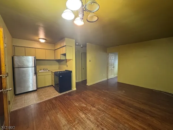 a view of a kitchen with a fridge and wooden floor
