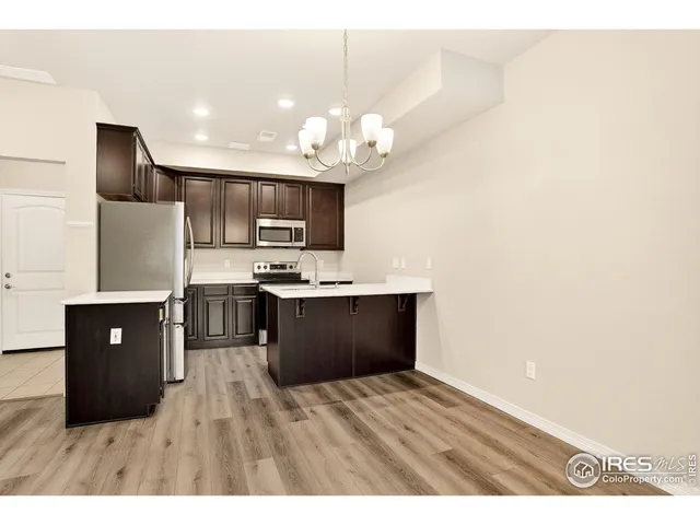 a kitchen with kitchen island granite countertop a refrigerator cabinets and wooden floor