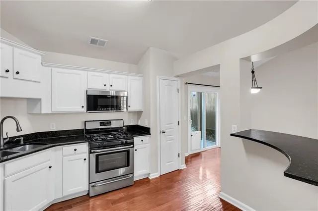 a kitchen with granite countertop a sink cabinets and stainless steel appliances