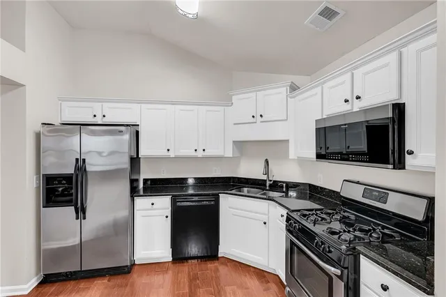 a kitchen with stainless steel appliances granite countertop a stove a refrigerator and a microwave