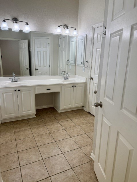 20724 Kearney Hill Road Pflugerville, TX 78660 - Photo 29 of 40 Dual vanity with white cabinetry, integrated sinks, chrome faucets, and an expansive wall mirror