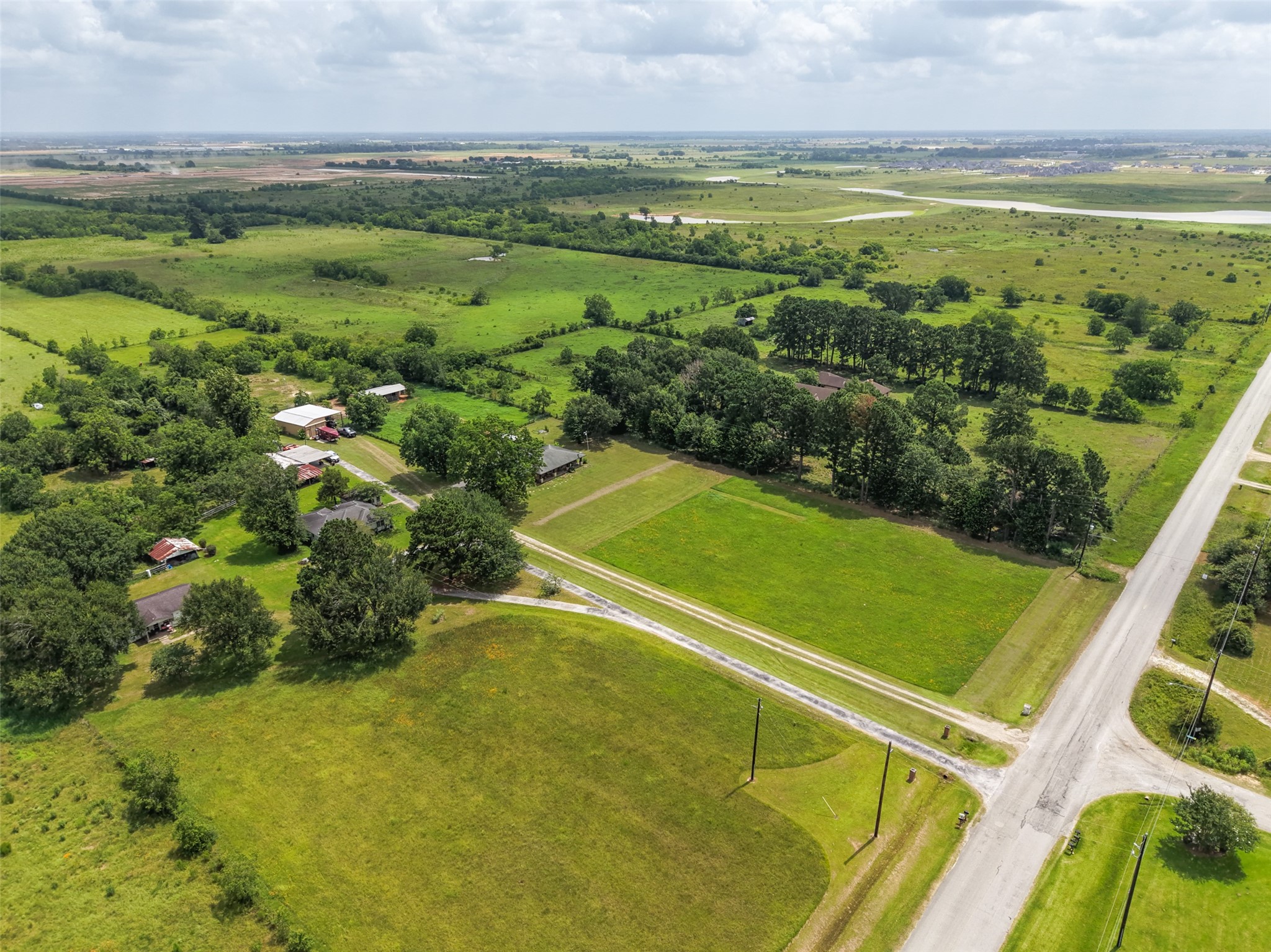 34366 Owens Road Hempstead, TX 77445 - Photo 29 of 46 Elevated view highlighting the property's open pasture, mature trees, multiple improvements, and extensive road frontage, showcasing the layout and surrounding countryside.