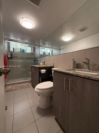 a bathroom with a granite countertop sink a toilet and a mirror