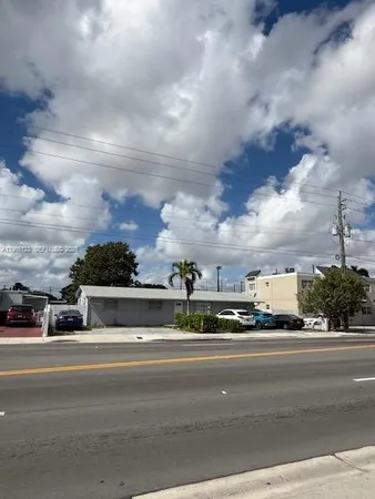 a front view of a building with lot of cars on road