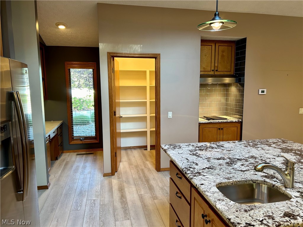 8763 Timber Edge Drive North Ridgeville, OH 44039 - Photo 8 of 40 Kitchen with hanging light fixtures, light hardwood / wood-style floors, stainless steel fridge, and backsplash