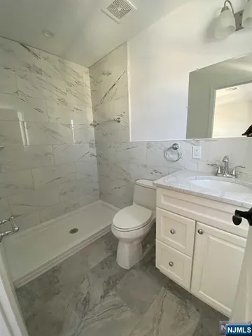 a bathroom with a granite countertop toilet a sink a mirror and shower