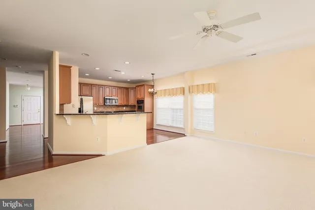 a view of kitchen and empty room with wooden floor