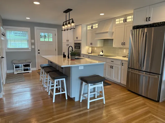 a kitchen with stainless steel appliances granite countertop a dining table chairs refrigerator sink and microwave