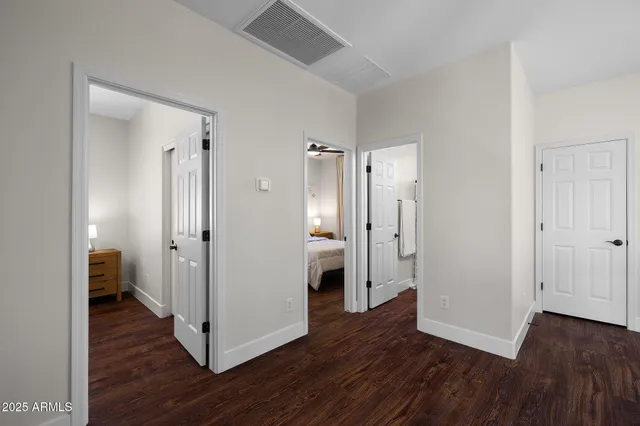 a view of a hallway with wooden floor and a bathroom
