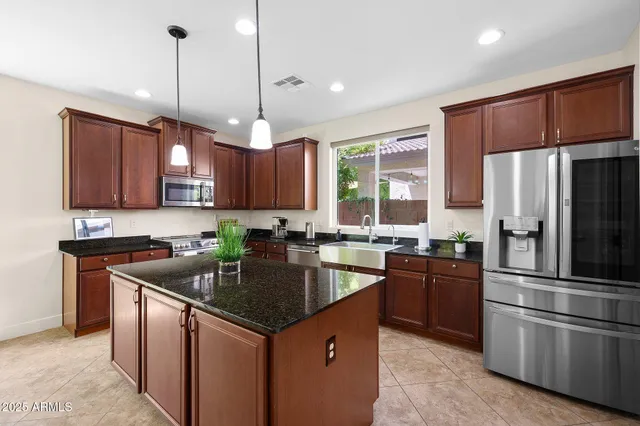 a kitchen with stainless steel appliances granite countertop a sink a stove a refrigerator a center island and cabinets
