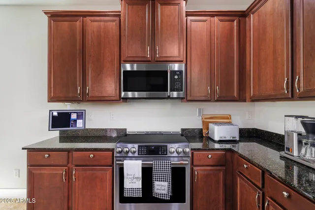a kitchen with stainless steel appliances granite countertop wooden cabinets a stove top oven