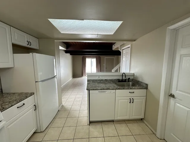 a kitchen with granite countertop a refrigerator and a stove top oven