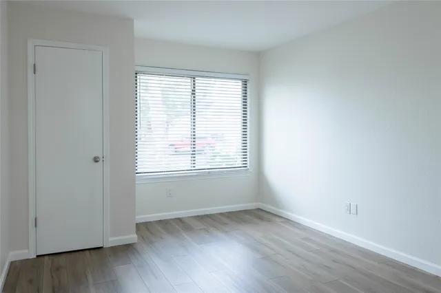 an empty room with wooden floor and window