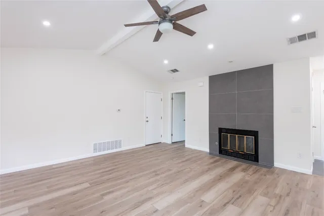 an empty room with wooden floor and a ceiling fan