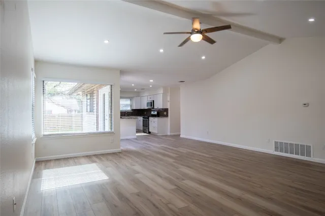a view of an empty room with a window and wooden floor