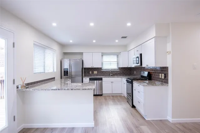 a kitchen with stainless steel appliances granite countertop a sink cabinets and wooden floor
