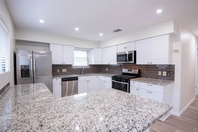 a kitchen with granite countertop a stove sink microwave and refrigerator