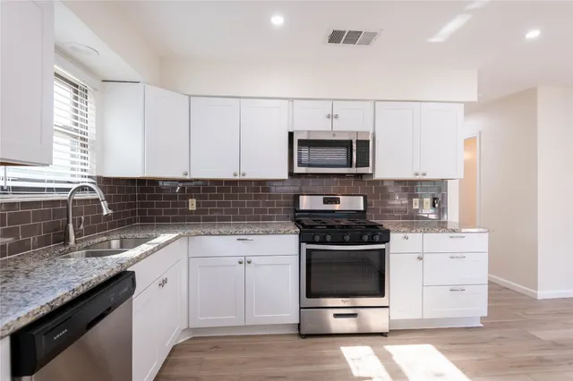 a kitchen with stainless steel appliances a stove sink microwave and cabinets