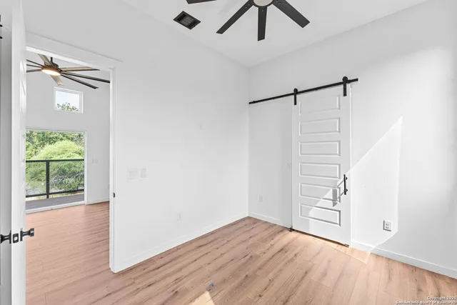 an empty room with wooden floor fan and windows