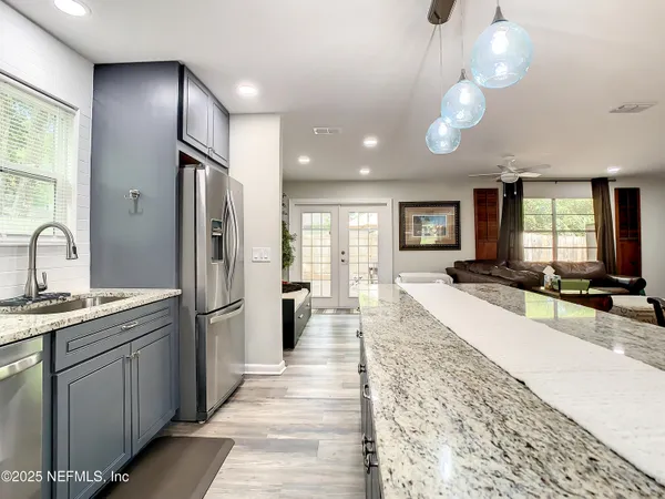 a large kitchen with stainless steel appliances a large counter top a sink a refrigerator and window