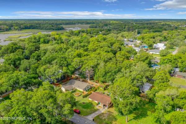 an aerial view of residential houses with outdoor space and trees