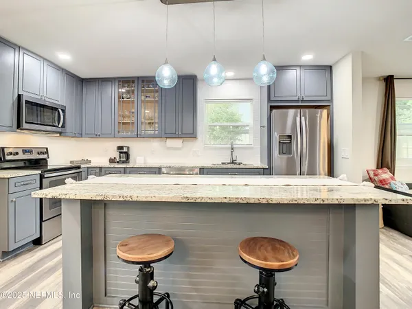 a kitchen with stainless steel appliances granite countertop a sink a stove a refrigerator cabinets and living room view