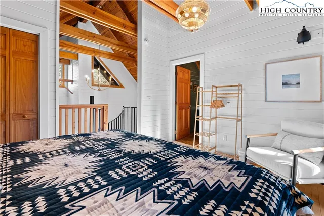 a bedroom with a bed and a dresser with wooden floor