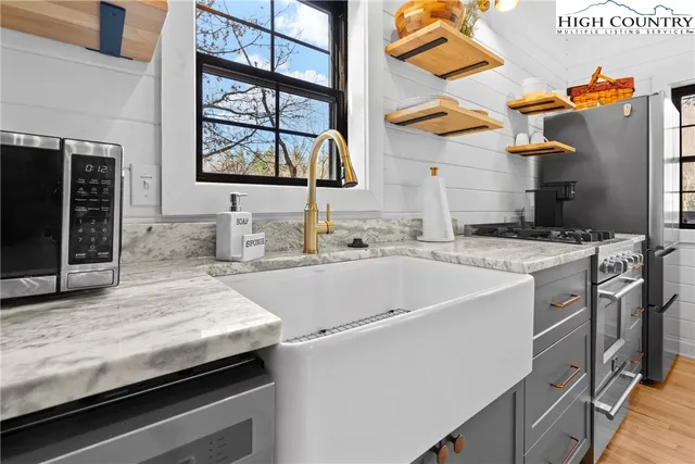 a utility room with stainless steel appliances granite countertop a sink and dishwasher a stove with wooden floor