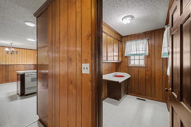 an empty room with chandelier fan and wooden floor