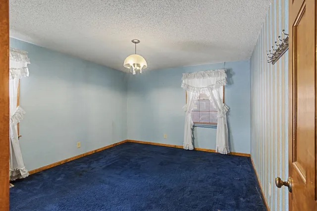 an empty room with windows chandelier and front door