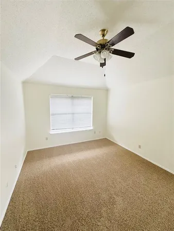 an empty room with a ceiling fan and window
